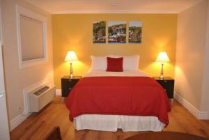 a bedroom with a red bed and two lamps at Arnold's Cove Inn in Arnold's Cove