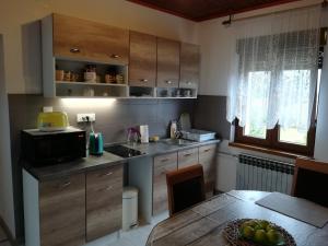 a kitchen with wooden cabinets and a table with a microwave at Apartment Arya in Korenica