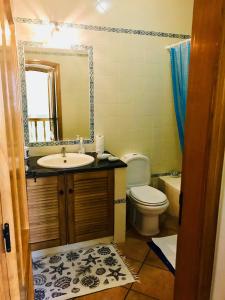 a bathroom with a sink and a toilet and a mirror at Bella & Gordinho GuestHouse in Lagos