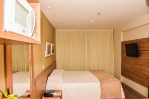 a small bedroom with a bed and a tv at Mont Blanc Suites Duque de Caxias in Duque de Caxias