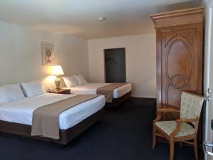 a bedroom with a bed, chair and a lamp at Saddle West Casino Hotel in Pahrump