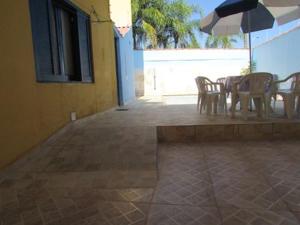 a patio with a table and chairs and an umbrella at Casa c/ Piscina - Ampla e Arejada Balneário Gaivota - 300 mts da Praia in Itanhaém