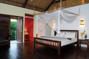 a bedroom with a bed with a mosquito net at Koh Yao Sunrise Villa in Ko Yao Noi