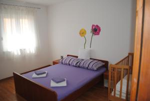 Un dormitorio con una cama con un jarrón de flores. en Apartments Vidolma en Povljana