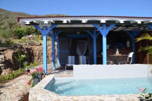 a swimming pool under a pergola next to a house at Les Hauts de la Baie in Terre-de-Bas