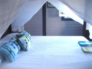 a bed with a blue pillow on top of it at Les Hauts de la Baie in Terre-de-Bas