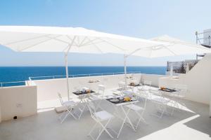 a balcony with white chairs and tables and an umbrella at Dimora Talenti in Polignano a Mare