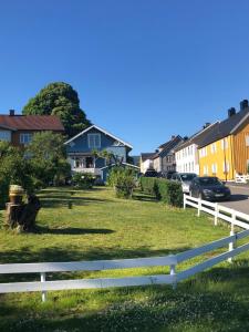 a white fence in front of a yard with houses at Charming Lakeside House with sauna in Lillehammer