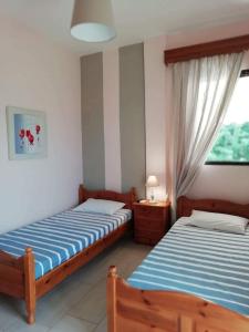 a bedroom with two beds and a window at Trantas Rooms in Paralía Skotínis