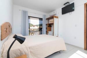 a bedroom with a bed with a television and a balcony at Residencial Los Abuelos in Bombinhas