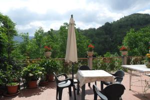 Casa delle Rose في Roa Marenca: فناء فيه مظلة وطاولات وكراسي