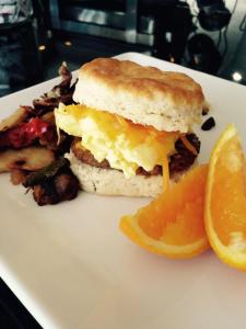 a breakfast sandwich on a plate with an orange slice at Hotel Pentagon in Arlington