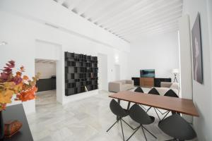 een witte woonkamer met een houten tafel en stoelen bij Casa Columela Cadiz in Cádiz