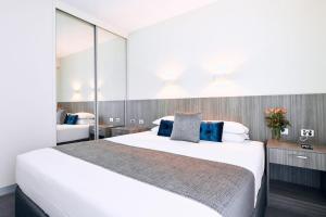 a bedroom with a large white bed with blue pillows at Club Laverton in Laverton +21 photos