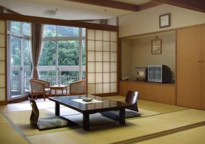 uma sala de estar com uma mesa e cadeiras e uma janela em Itoen Hotel Shikisai em Yugawara