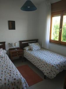 a bedroom with two beds and a lamp and a window at Chalet en el Orbigo in La Bañeza