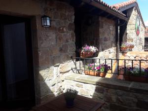 a stone building with potted plants on a balcony at Posada Rural La Piñorra in Vinuesa