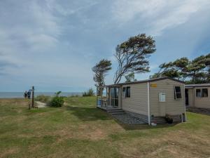 ein winziges Haus auf einem Feld mit dem Ozean im Hintergrund in der Unterkunft Pohara Beach TOP 10 Holiday Park in Pohara