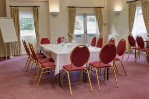 a conference room with a white table and red chairs at The Cedars Hotel in Stowmarket