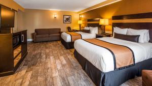 a hotel room with a bed, chair, and nightstand at Best Western Plus Newark Airport West in Newark