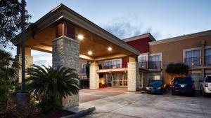 un grand bâtiment avec des voitures garées devant lui dans l'établissement Best Western Plus Atrium Inn, à Schertz