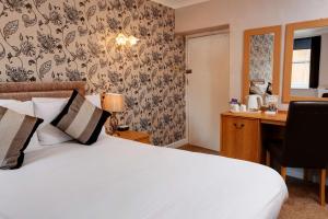 a bedroom with a bed and a desk with a computer at Best Western The George Hotel, Swaffham in Swaffham