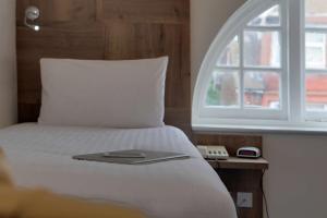 a bed with a book on it next to a window at Best Western White House Hotel in Watford +36 photos