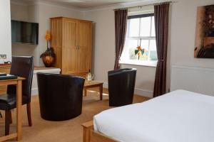a room with a bed, chair, desk and a television at Best Western Lord Haldon Hotel in Exeter