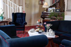 a living room with blue chairs and a piano at Best Western Lord Haldon Hotel in Exeter