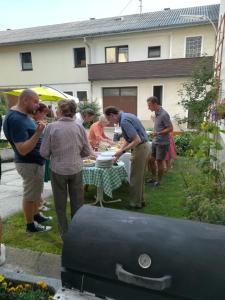 eine Gruppe von Menschen, die um einen Tisch mit einem Grill stehen in der Unterkunft Privatzimmer Dimitrova in Ulrichsberg