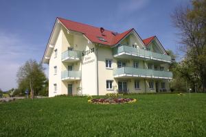 a large white building with a red roof on a green field at Hotel & Restaurant Karpfen in Illmensee