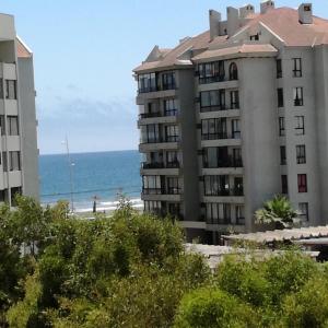 un edificio en la playa con el océano en el fondo en Condominio Reino de Italia, Serena, en La Serena