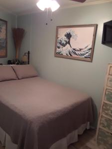 a bedroom with a bed and a painting of a wave at 'It's All Good!' in Corpus Christi