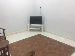 a living room with a television on a white wall at Taman Rambai Utama Homestay in Malacca