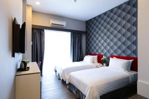 a hotel room with two beds and a window at Cenang Plaza Beach Hotel in Pantai Cenang