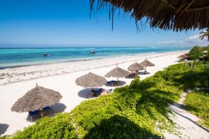 a group of straw umbrellas on a beach at Zanzibar Queen Hotel in Matemwe