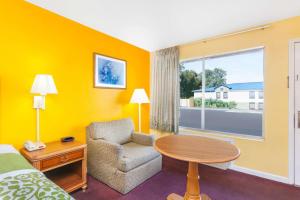 a hotel room with a bed and a chair and a table at Days Inn by Wyndham Jacksonville in Jacksonville