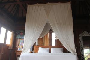 Schlafzimmer mit Himmelbett und weißen Vorhängen in der Unterkunft Ogek Home Stay in Ubud