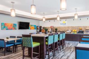 a restaurant with a bar with colorful chairs at Days Inn & Suites by Wyndham Katy in Katy