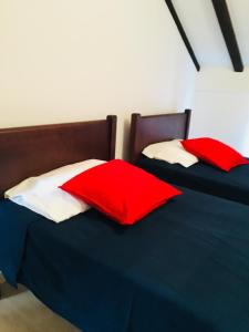 two beds with red and white pillows in a room at casadaeiradeangeja in Angeja