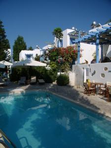 a swimming pool with chairs and umbrellas and a house at Panorama Paros in Parikia