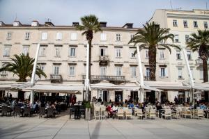 a group of people sitting at tables in front of a building at Luxury rooms Skystar-Split in Split
