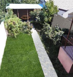 a small backyard with a lawn with a stone pathway at REST Guest House in Yerevan