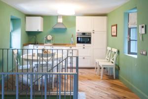 una cucina con pareti verdi e tavolo e sedie di Isola Bella Apartments - Via Villa 9 a Stresa