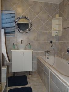 a bathroom with a sink and a tub and a mirror at Beach House On 18p Repens in Mossel Bay