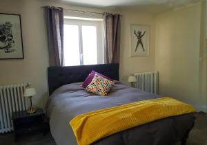 ein Schlafzimmer mit einem Bett mit einer lila Decke und einem Fenster in der Unterkunft La Roseraie in Sentheim
