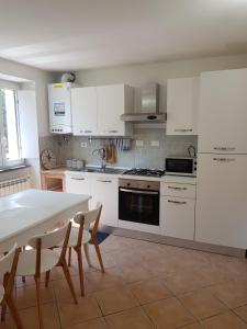 a kitchen with white cabinets and a table and chairs at Villaggio Fiorito Casale in Pignone