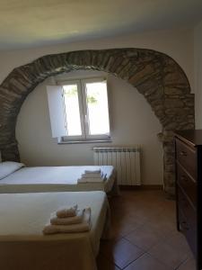 皮尼奧內的住宿－Villaggio Fiorito Casale，一间卧室设有两张床和一个带毛巾的窗户。