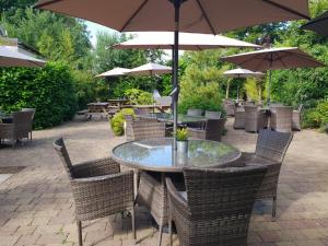 un patio al aire libre con mesas, sillas y sombrillas en Fairburn Hotel, en Mauchline