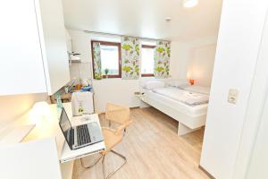 Kleines Zimmer mit einem Bett und einem Laptop auf einem Schreibtisch. in der Unterkunft Aparthotel B & L in Bremen